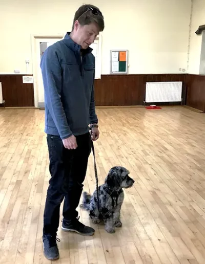 A dog owner with his dog in the village hall in Ockely having completed a dog training class.